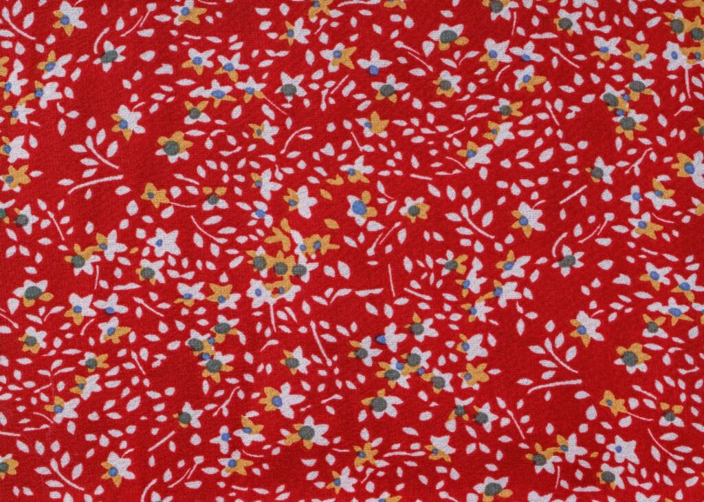 Colorful floral pattern featuring small flowers on a vivid red fabric background.